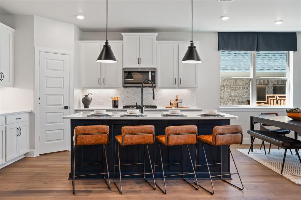 8717 Kentucky Derby Street Pilot Point, TX 76258 - Photo 2 of 18 a kitchen with granite countertop a stove a sink a dining table and chairs