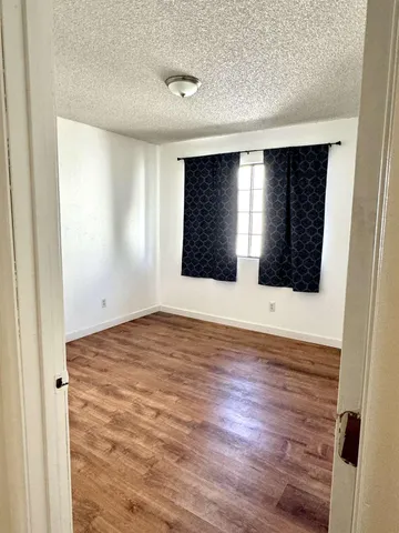 a view of an empty room with window and wooden floor