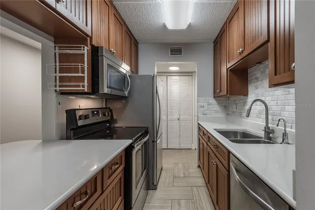 a kitchen with stainless steel appliances granite countertop a sink a stove and a refrigerator