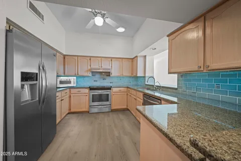 a kitchen with stainless steel appliances granite countertop a sink refrigerator and cabinets