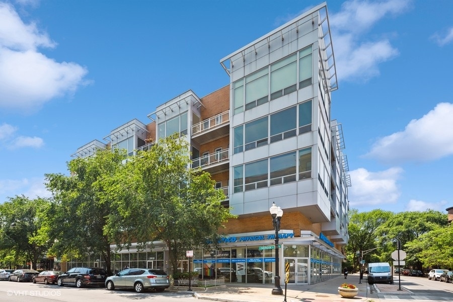 a front view of a building with lot of cars and trees