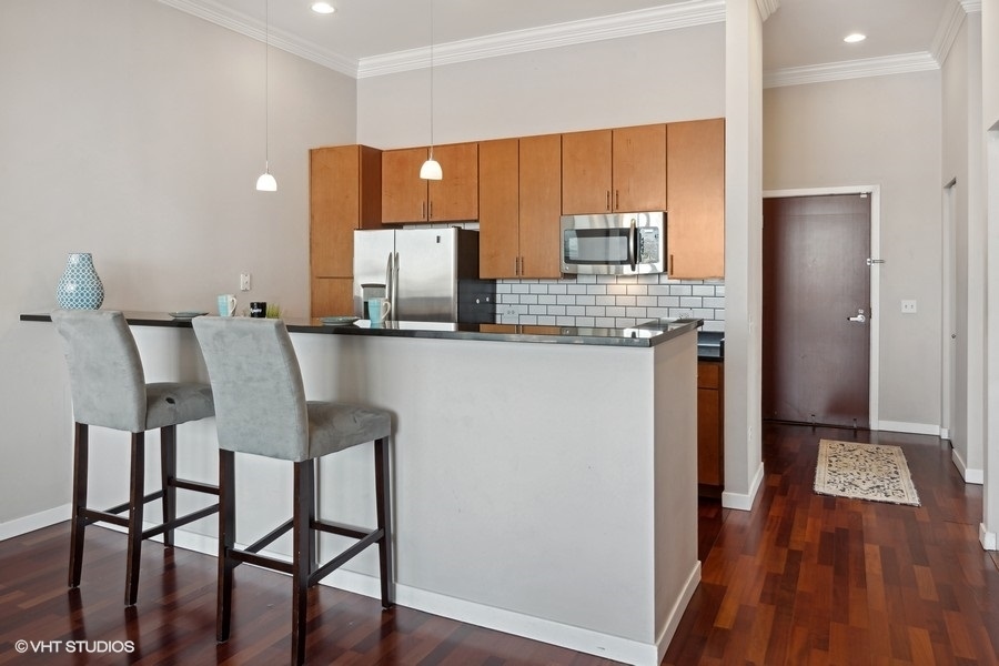 3920 North Sheridan Road, Unit 504 Chicago, IL 60613 - Photo 8 of 21 a kitchen with stainless steel appliances granite countertop a table chairs refrigerator and sink