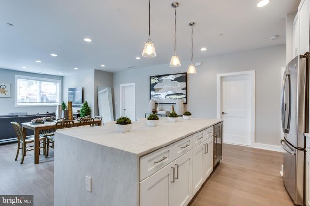 a kitchen with stainless steel appliances granite countertop a sink a stove a refrigerator and white cabinets