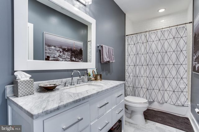 a bathroom with a granite countertop sink a toilet and shower