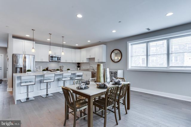 a kitchen with stainless steel appliances kitchen island granite countertop a dining table chairs and white cabinets