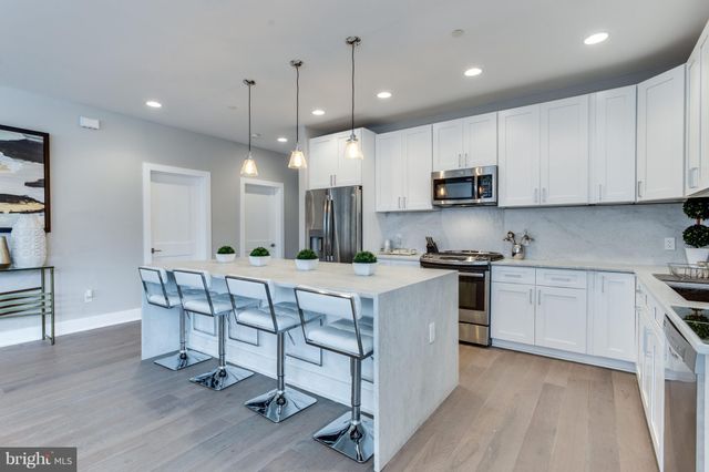 a kitchen with stainless steel appliances kitchen island granite countertop a stove a sink and a refrigerator