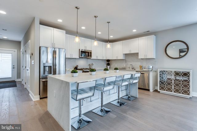 a kitchen with kitchen island granite countertop a stove a sink a refrigerator and a oven with wooden floor