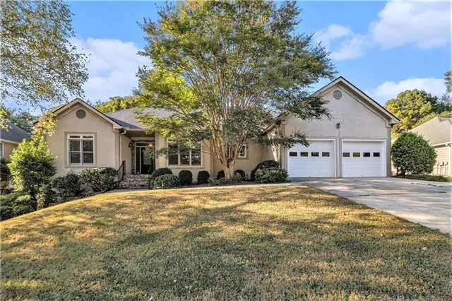 a view of a house with a yard and large tree