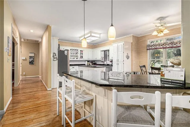 a view of a kitchen with kitchen island granite countertop wooden floor and stainless steel appliances