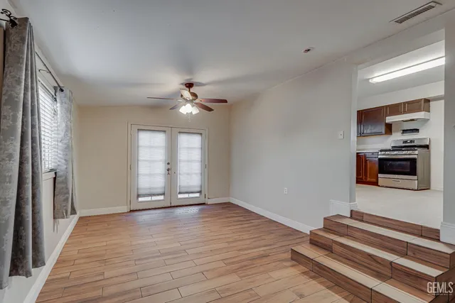 a view of empty room with wooden floor and fan