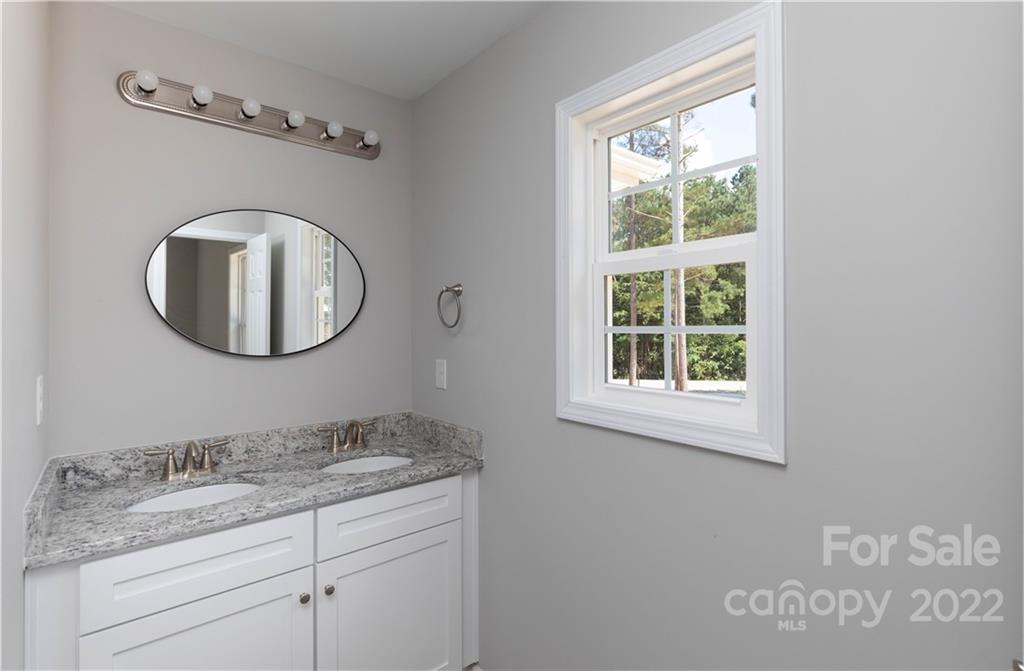 6184 Hopewell Road Hickory Grove, SC 29717 - Photo 25 of 30 a bathroom with a granite countertop toilet a sink and a mirror