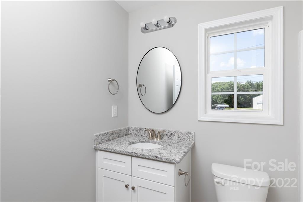 6184 Hopewell Road Hickory Grove, SC 29717 - Photo 28 of 30 a bathroom with a granite countertop toilet a sink and a mirror