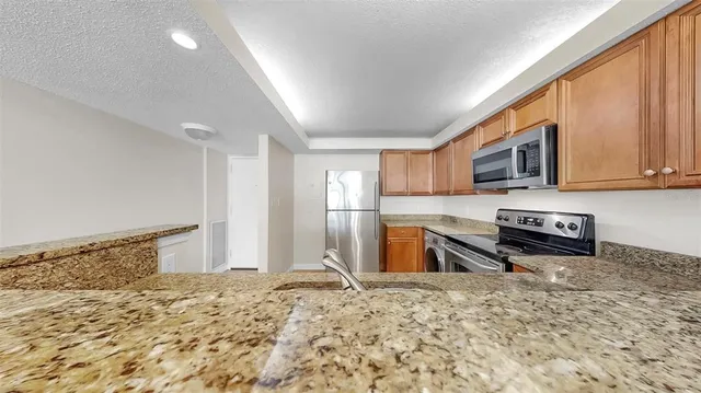 a kitchen with stainless steel appliances granite countertop a refrigerator stove top oven and sink