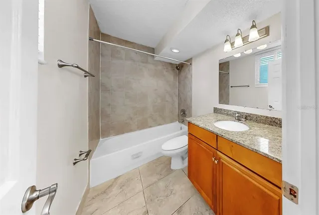 a bathroom with a granite countertop sink a toilet a mirror and shower