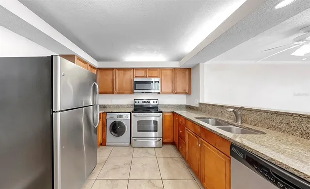 a kitchen with stainless steel appliances granite countertop a refrigerator sink and stove