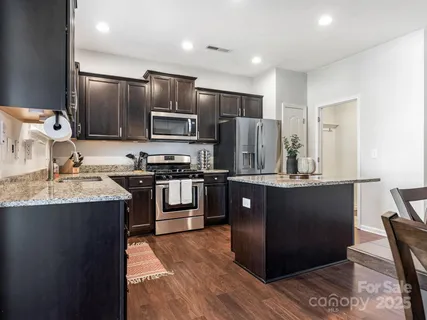 a kitchen with stainless steel appliances granite countertop a refrigerator and a stove top oven