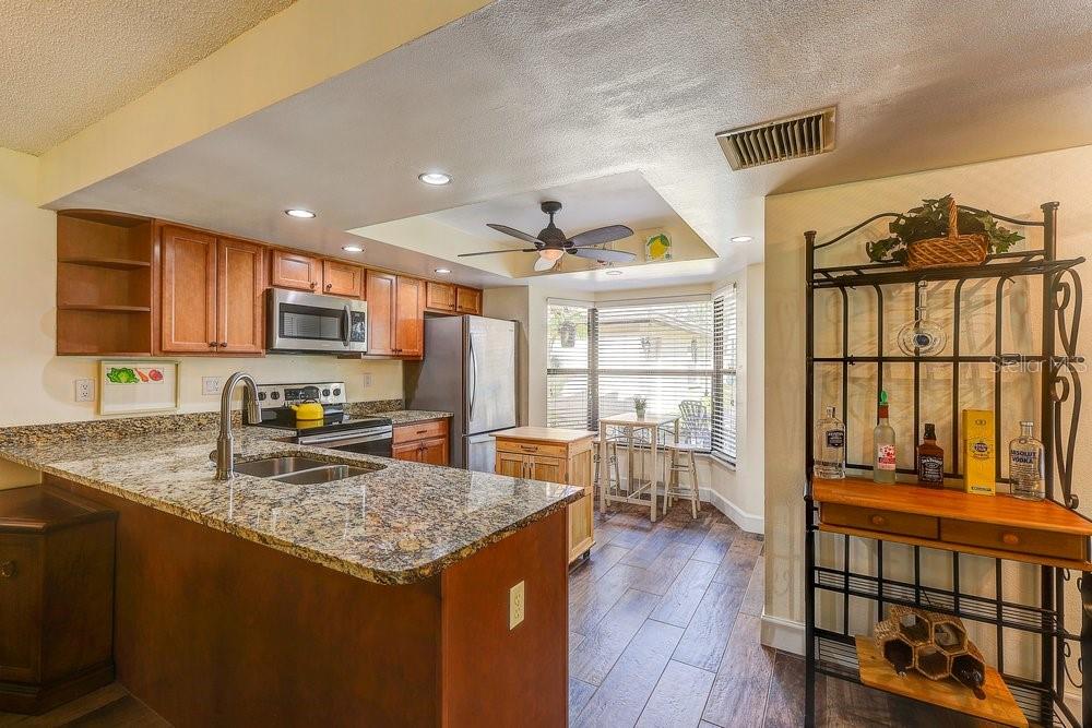 3454 Niblick Court New Port Richey, FL 34655 - Photo 11 of 54 a kitchen with stainless steel appliances granite countertop a stove top oven a sink a dining table and chairs with wooden floor