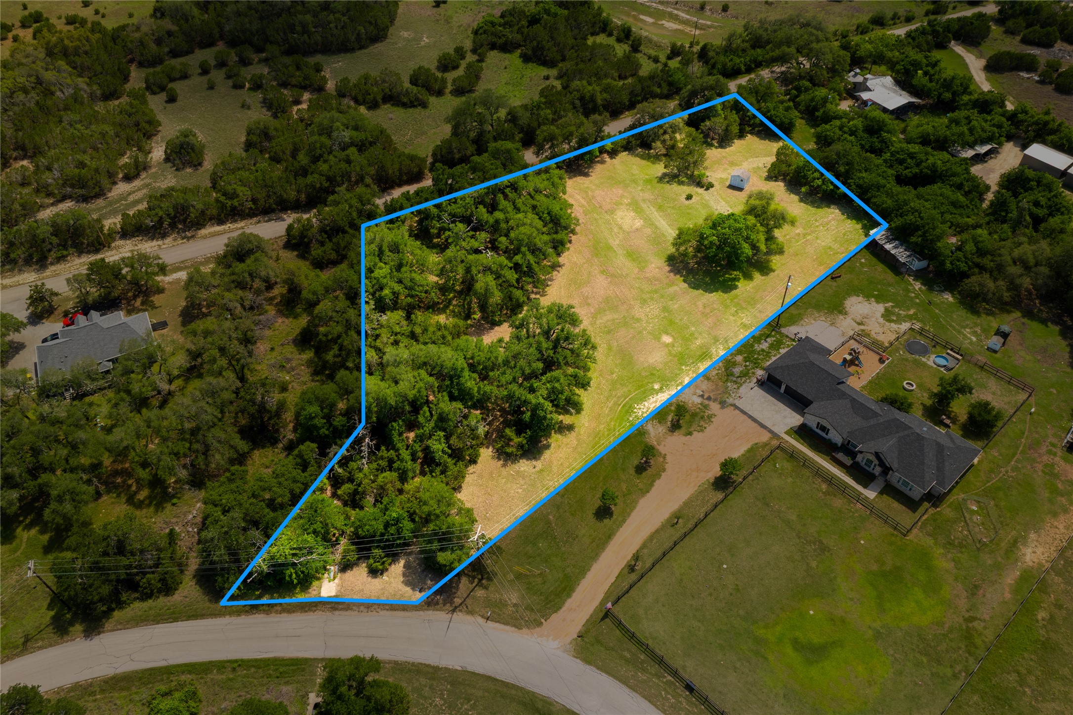 187 Beauchamp Road Dripping Springs, TX 78620 - Photo 10 of 19 Expansive raw land parcel featuring mature trees, a partially cleared area, and direct road frontage