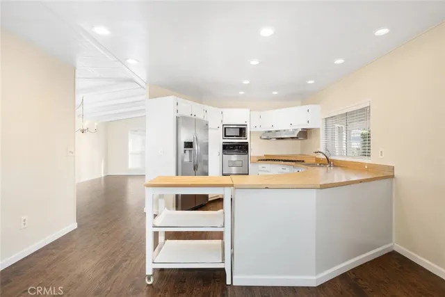 a view of kitchen with kitchen island stainless steel appliances wooden floor and view living room