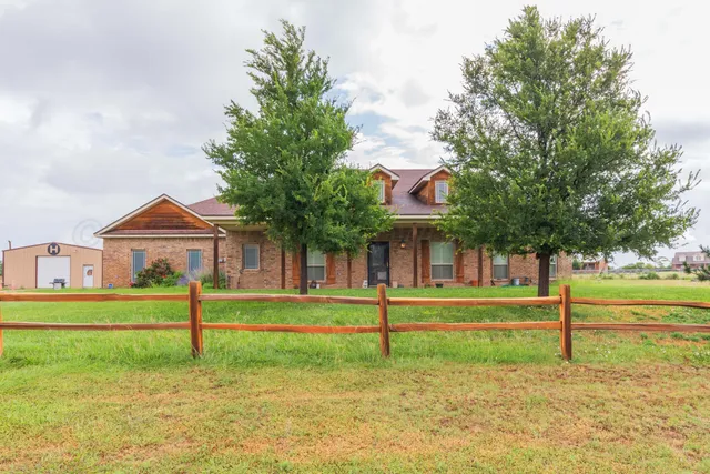 a view of a house with a big yard and large trees