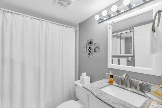 a bathroom with a granite countertop sink vanity mirror and toilet
