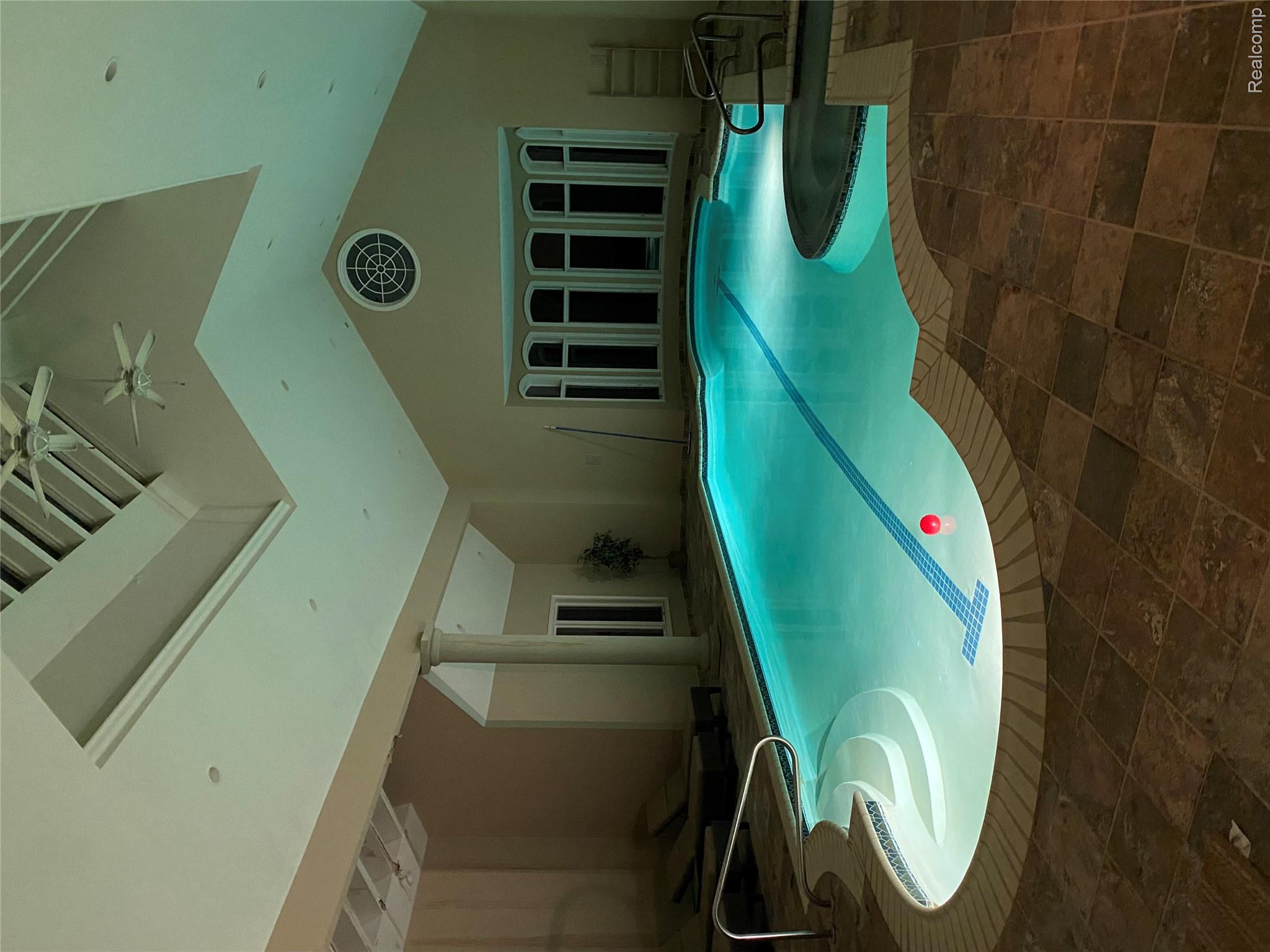 5165 Abbey Drive Rochester, MI 48306 - Photo 5 of 66 Indoor pool featuring a unique freeform shape, integrated spa, and tiled surround