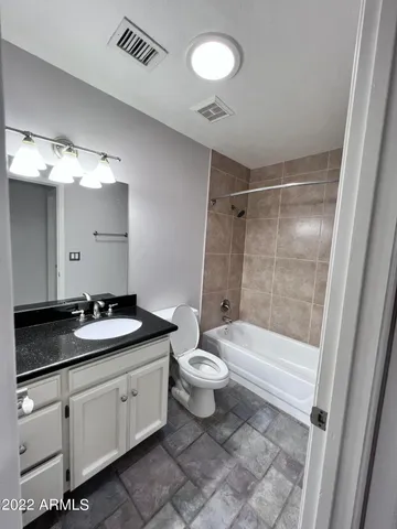 a bathroom with a granite countertop sink toilet a large mirror a bathtub and shower