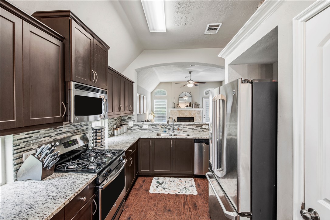 3014 Positano Loop Bryan, TX 77808 - Photo 11 of 23 a kitchen with stainless steel appliances granite countertop a stove top oven a sink and a refrigerator
