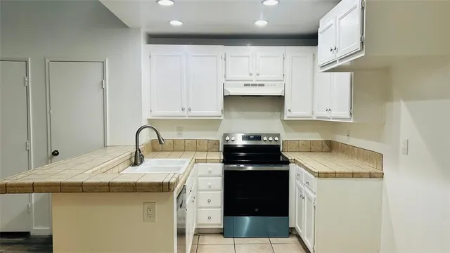 a kitchen with granite countertop a sink a stove and cabinets
