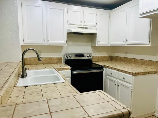 a kitchen with granite countertop a stove a sink and a microwave
