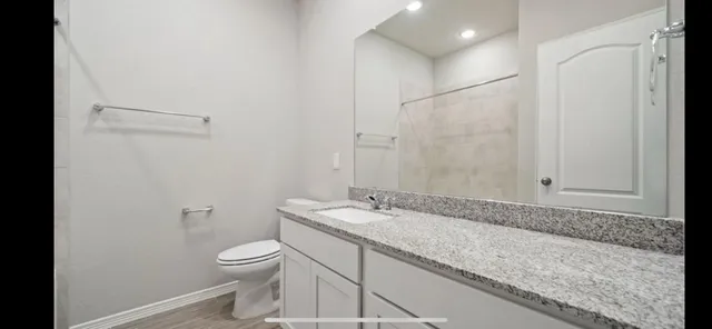 a bathroom with a granite countertop sink a toilet and a shower