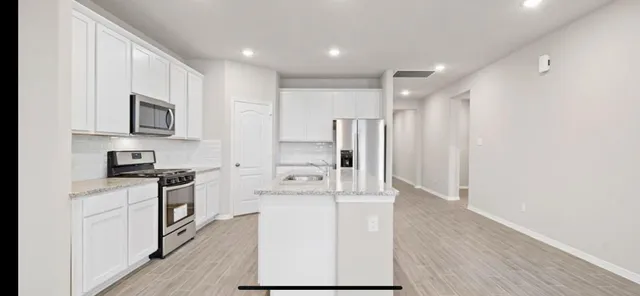 a kitchen with stainless steel appliances granite countertop a refrigerator stove and sink