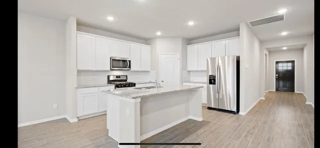 a kitchen with stainless steel appliances granite countertop a refrigerator stove and sink