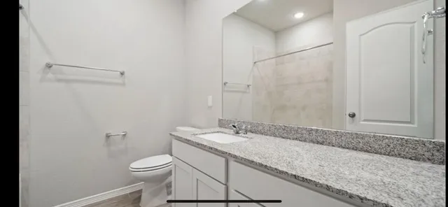 a bathroom with a granite countertop sink a toilet and shower
