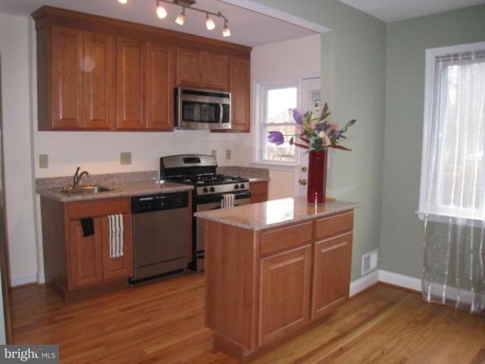 a kitchen with stainless steel appliances granite countertop a sink a stove a microwave and wooden floors