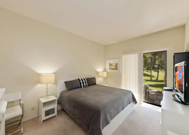 a bedroom with a bed and a flat tv screen on a dresser