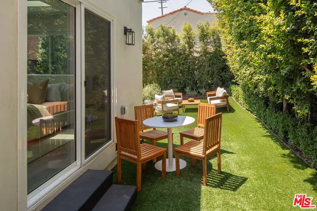 a patio with table and chairs and potted plants