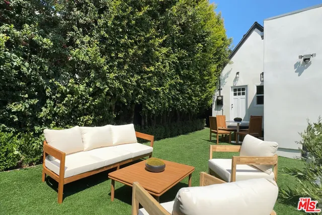 a view of a patio with couches table and chairs with plants and trees