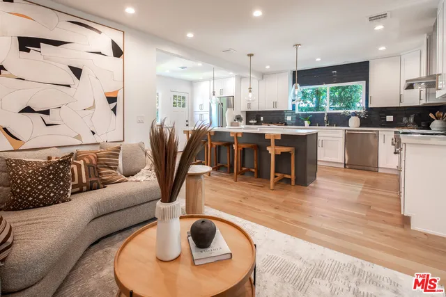 a living room with stainless steel appliances furniture and a kitchen view