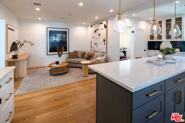 a living room with furniture kitchen area and a chandelier