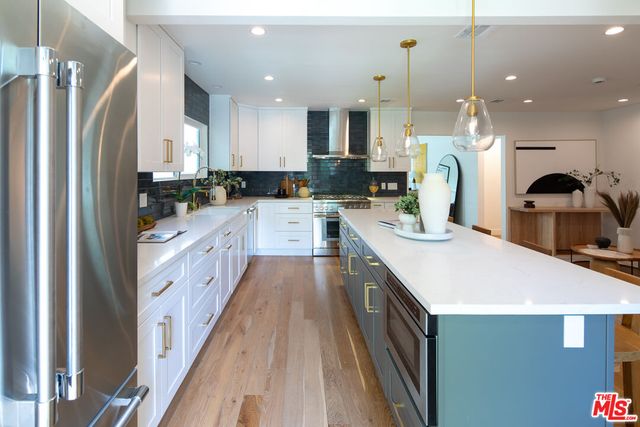 a large kitchen with stainless steel appliances kitchen island a stove a sink a refrigerator and a cabinets