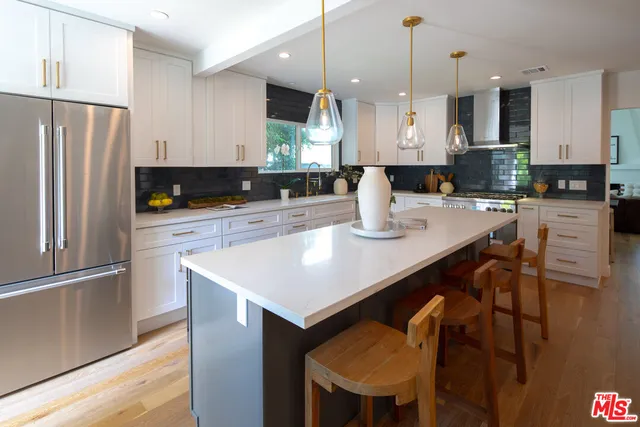 a kitchen with stainless steel appliances granite countertop a sink a stove a refrigerator a center island and a cabinets