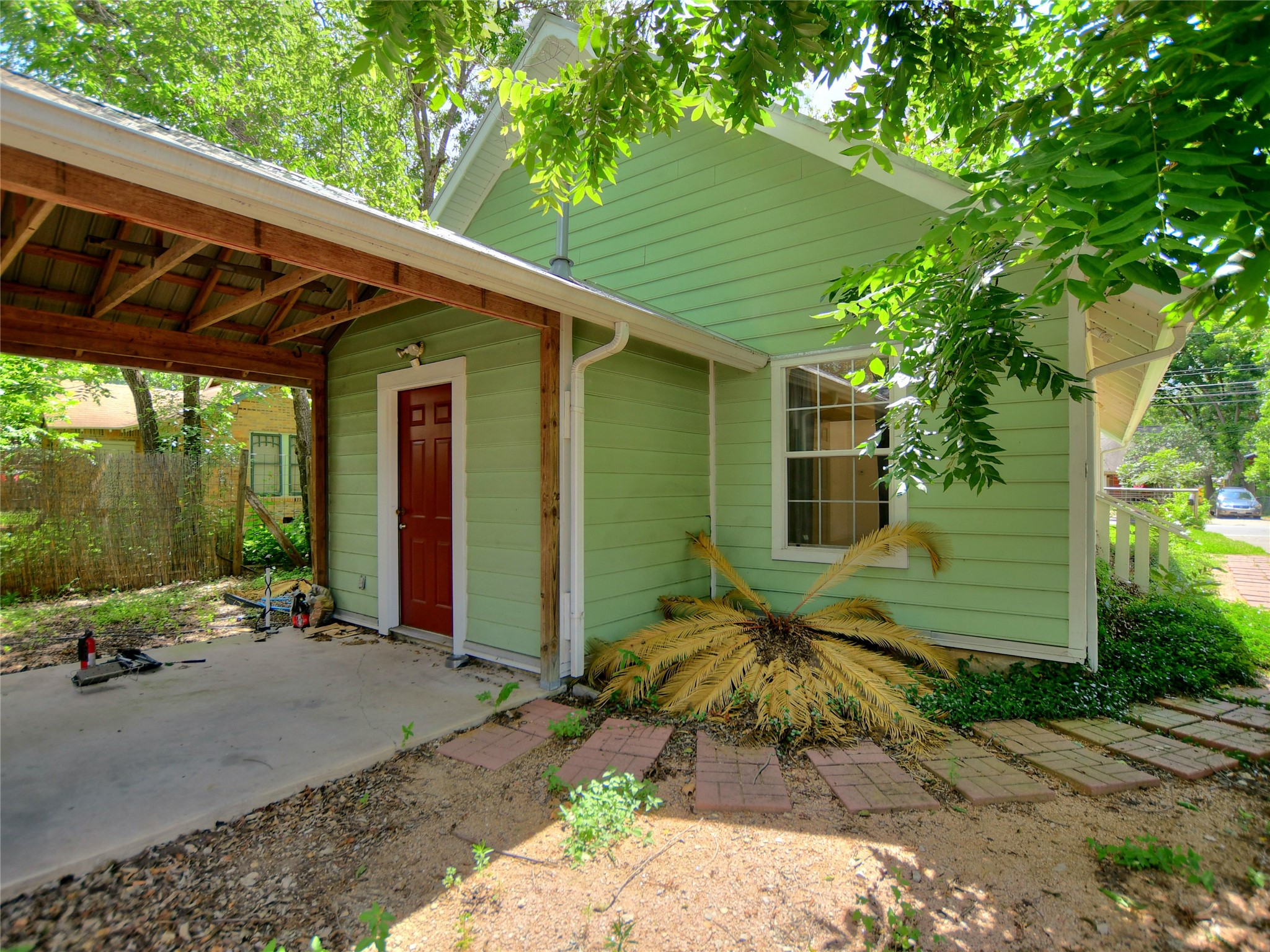 4604 Red River Street, Unit A Austin, TX 78751 - Photo 15 of 15 Green siding exterior with a covered carport featuring exposed wood beams and a metal roof