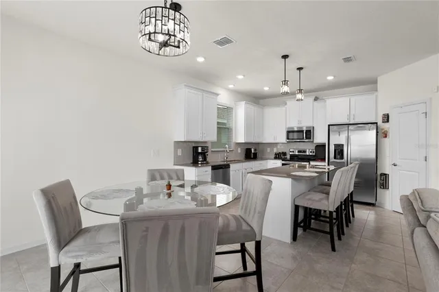 a kitchen with a dining table chairs refrigerator and cabinets