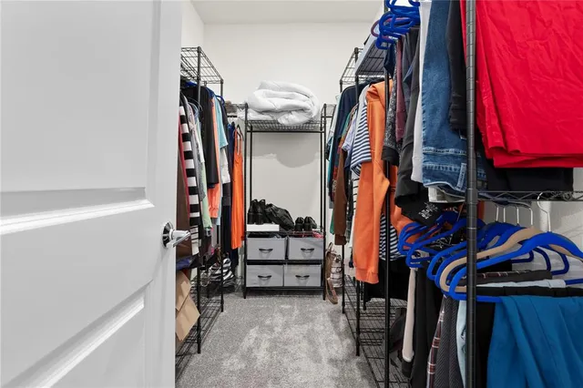 a view of walk in closet with clothes and shoes