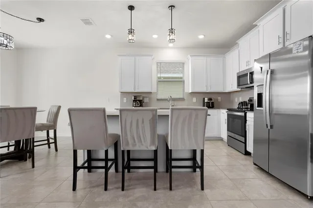 a kitchen with kitchen island a dining table chairs stainless steel appliances and cabinets