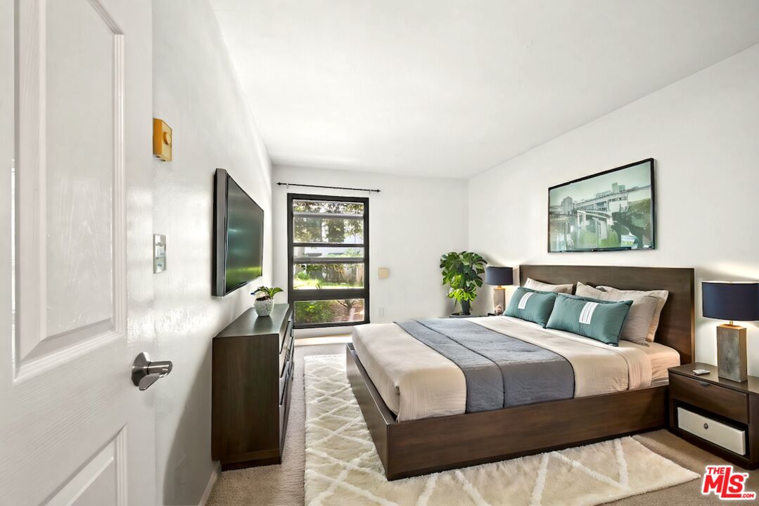 7765 West 91st Street, Unit F1110 Playa del Rey, CA 90293 - Photo 13 of 22 a bedroom with a bed lamp and a large window