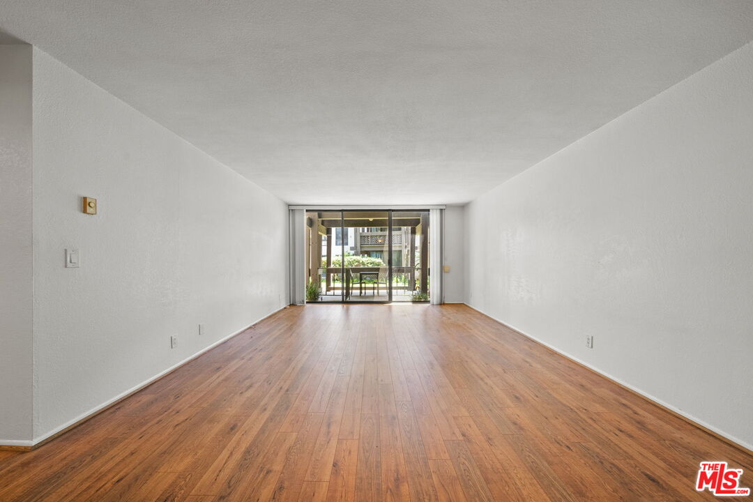7765 West 91st Street, Unit F1110 Playa del Rey, CA 90293 - Photo 2 of 22 a view of an empty room with wooden floor and a window