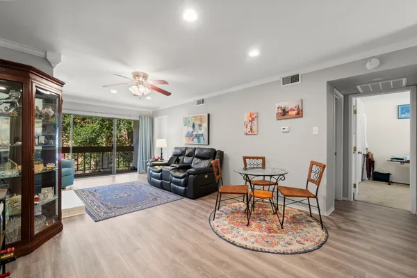 a living room with furniture kitchen view and a wooden floor