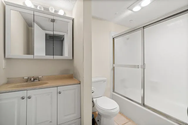 a bathroom with a granite countertop sink toilet and shower